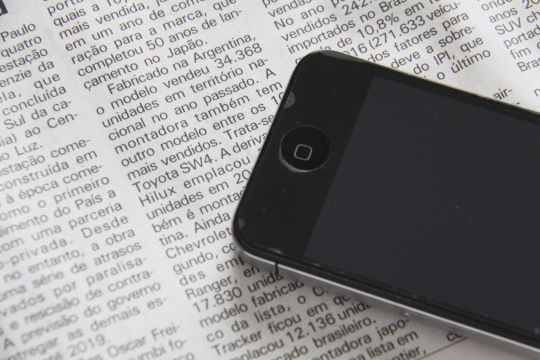 英字新聞の上に置かれたスマートフォン